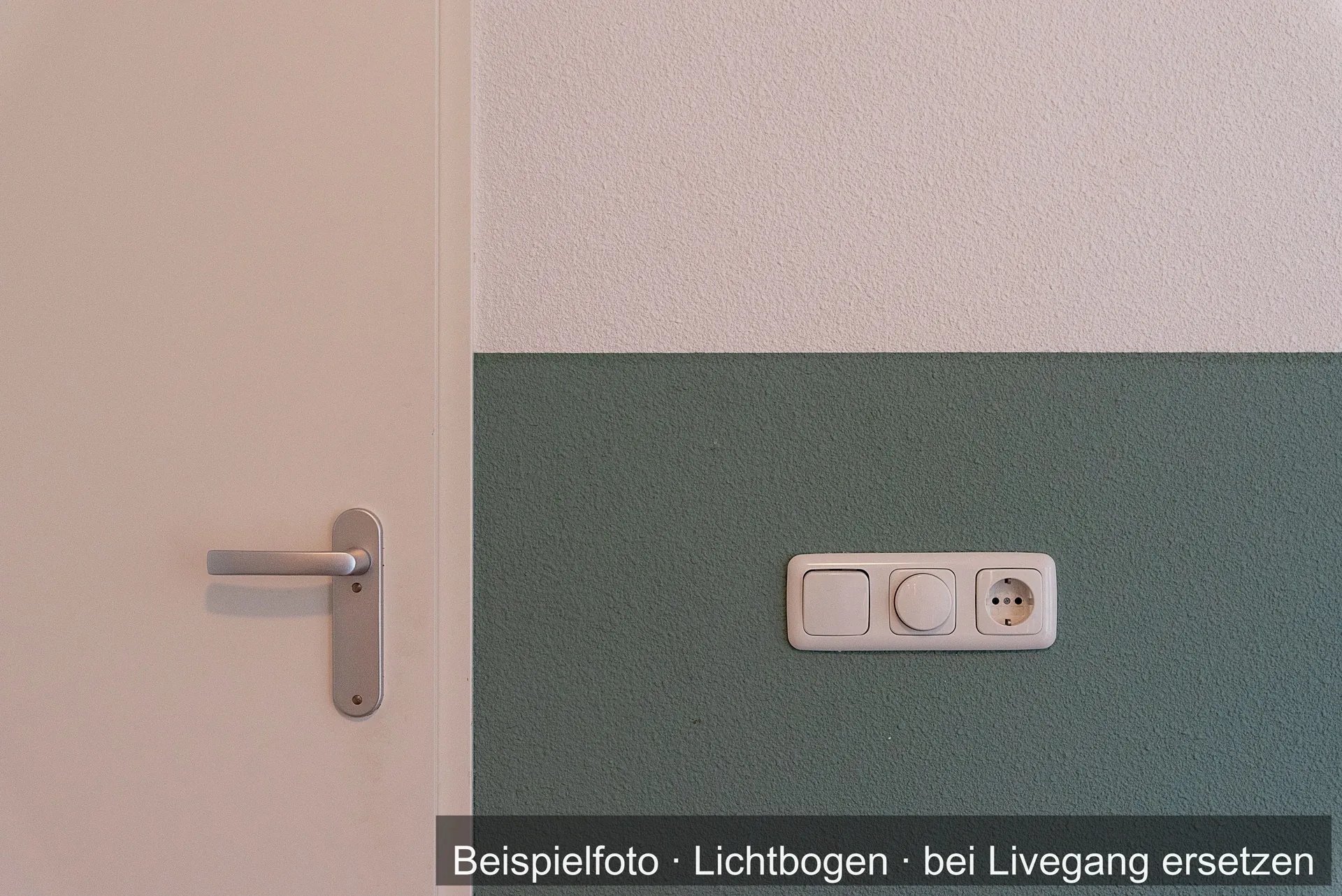 Tür neben einer zweifarbig gestrichenen Wand, unten Graugrün, oben hell, mit Schalter und Steckdose.