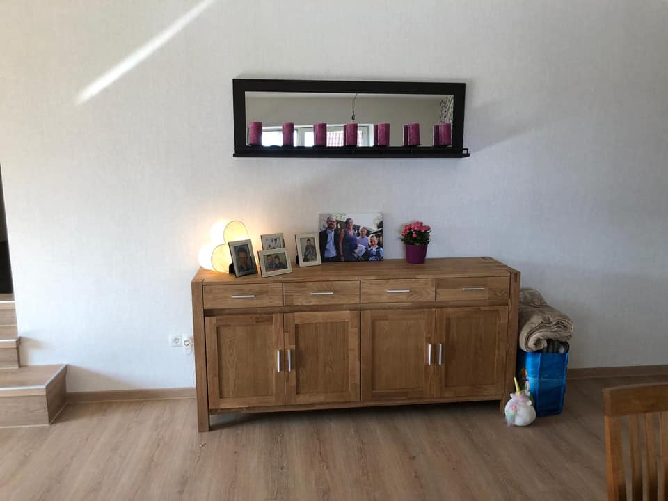 Helle Wand mit Sideboard und Wandregal im selben Wohnraum.