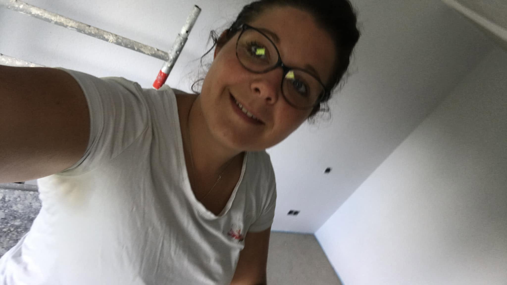 Lisa Louis in weißer Arbeitskleidung in einem frisch gestrichenen Raum, von ihr selbst aufgenommen.