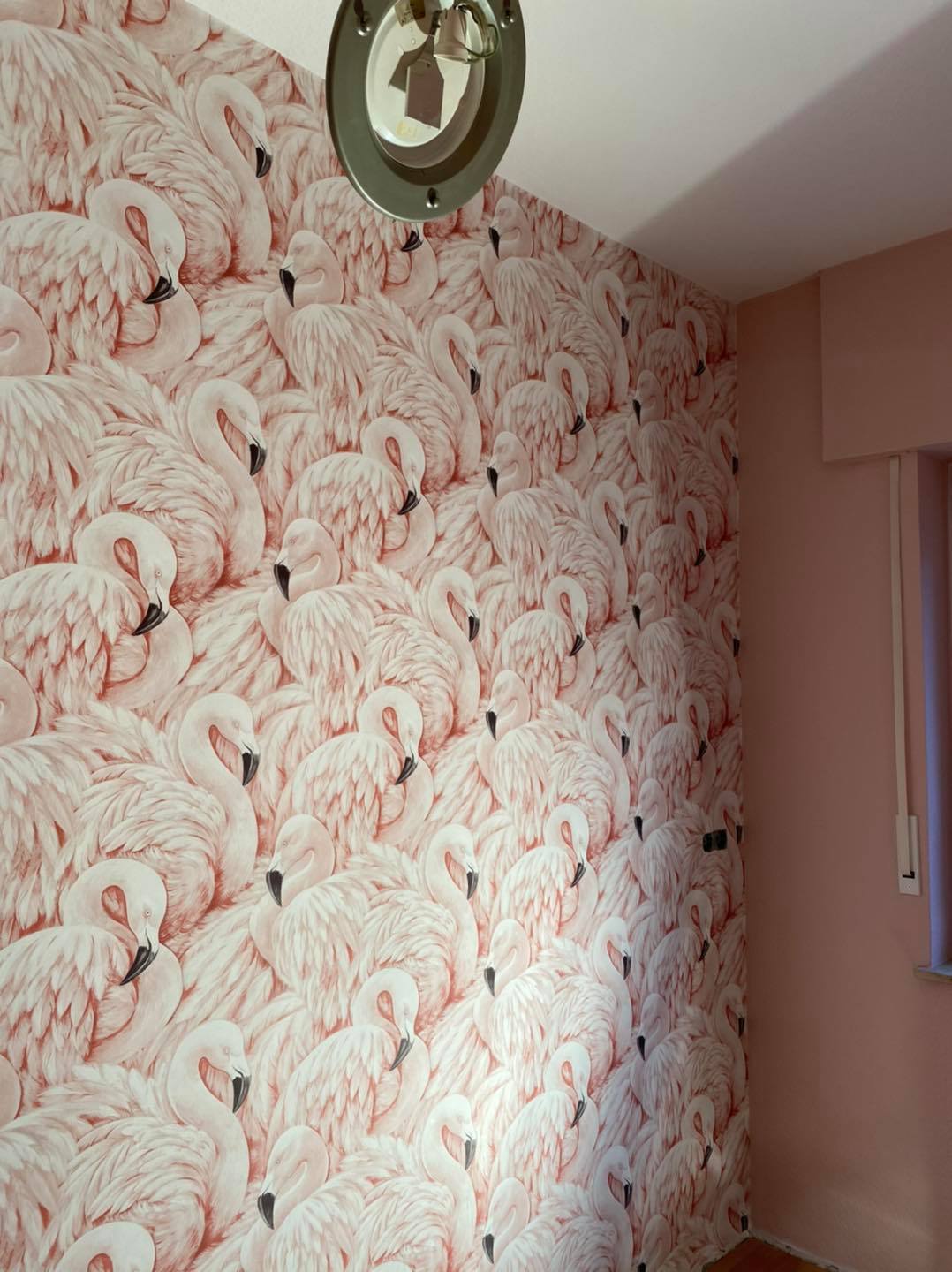 Ganze Flurwand mit rosé-weißer Flamingo-Tapete unter einer Deckenleuchte.